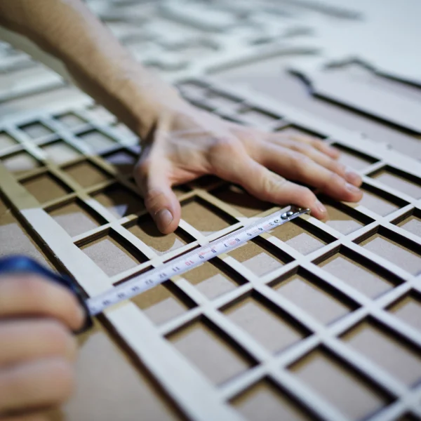 Une personne découpe un morceau de bois à l'aide d'une règle, illustrant le processus de découpe laser sur mesure.