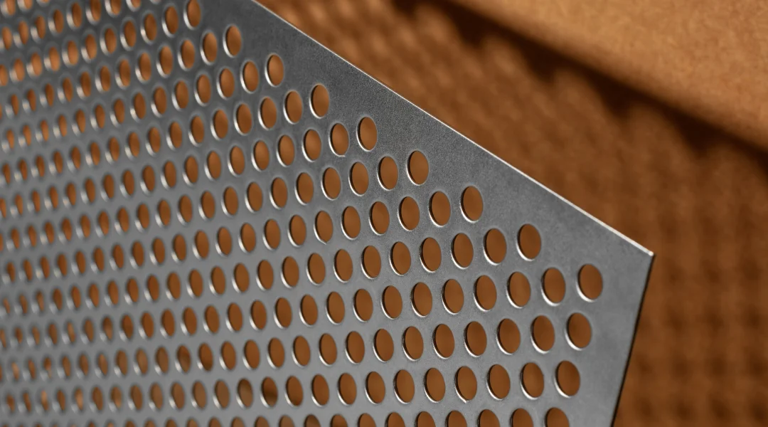 Gros plan sur une surface métallique perforée, illustrant le pliage d'acier sur mesure.