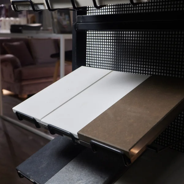 Un présentoir de carreaux dans un magasin, avec un canapé à proximité, mettant en avant le pliage d'acier sur mesure.